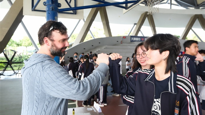 大明學子愉快與外國朋友交談,把英語學習化為日常互動,展現自信與國際視野。